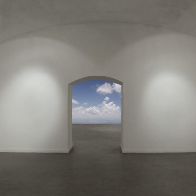 Zdjęcie wnętrza galerii z białymi ścianami i szarą podłogą. W centrum przejście do drugiej sali, z zaokrągloną górną krawędzią. W miejscu, gdzie powinna być ściana następnego pomieszczenia widok na niebo z chmurami.
